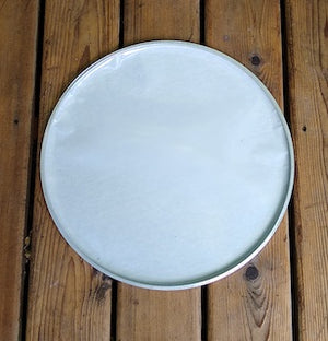 Bottom view of a GOPE drum head. White plastic interior of a napa head. Background of wood.