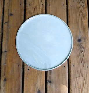 Back side view of a GOPE drum head made of napa. Sitting on a wooden porch.
