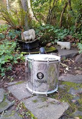 Repinique drum outside in front of a fountain. Plants and stone walkway background.